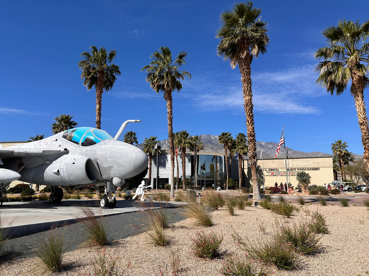 The exterior of the Palm Springs Air Museum, along with a vintage plane on display.